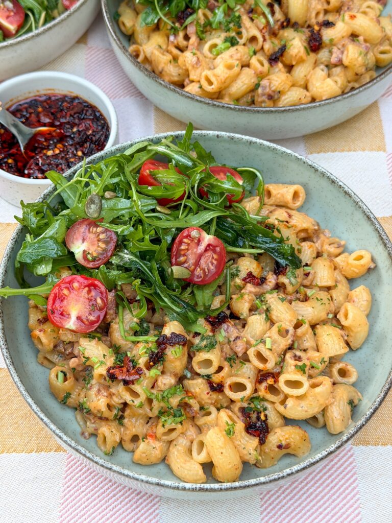 Pasta roomsaus met crispy chili olie en spek geserveerd met salade