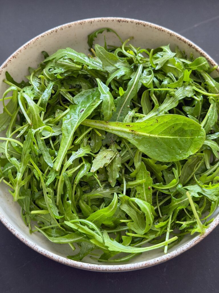 Rucola mengen met olijfolie, citroen, zwarte peper en zout