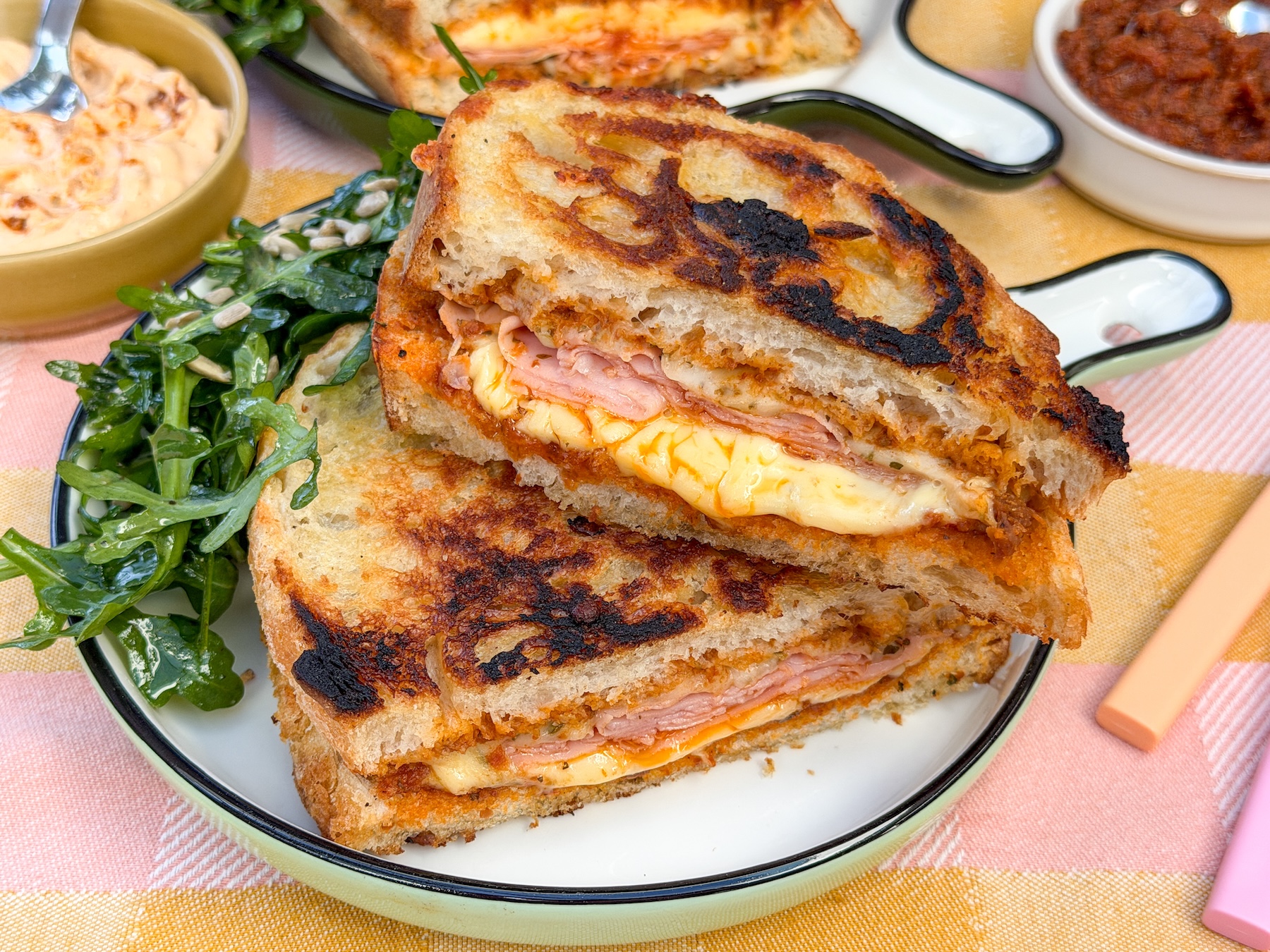 Tosti met pesto arrabbiata en mortadella met salade op bord