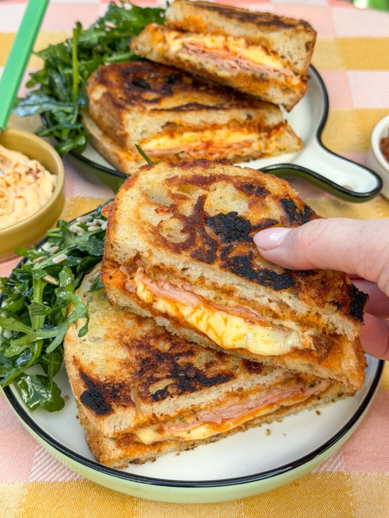 Tosti met pesto arrabbiata en mortadella - hand pakt tosti vast