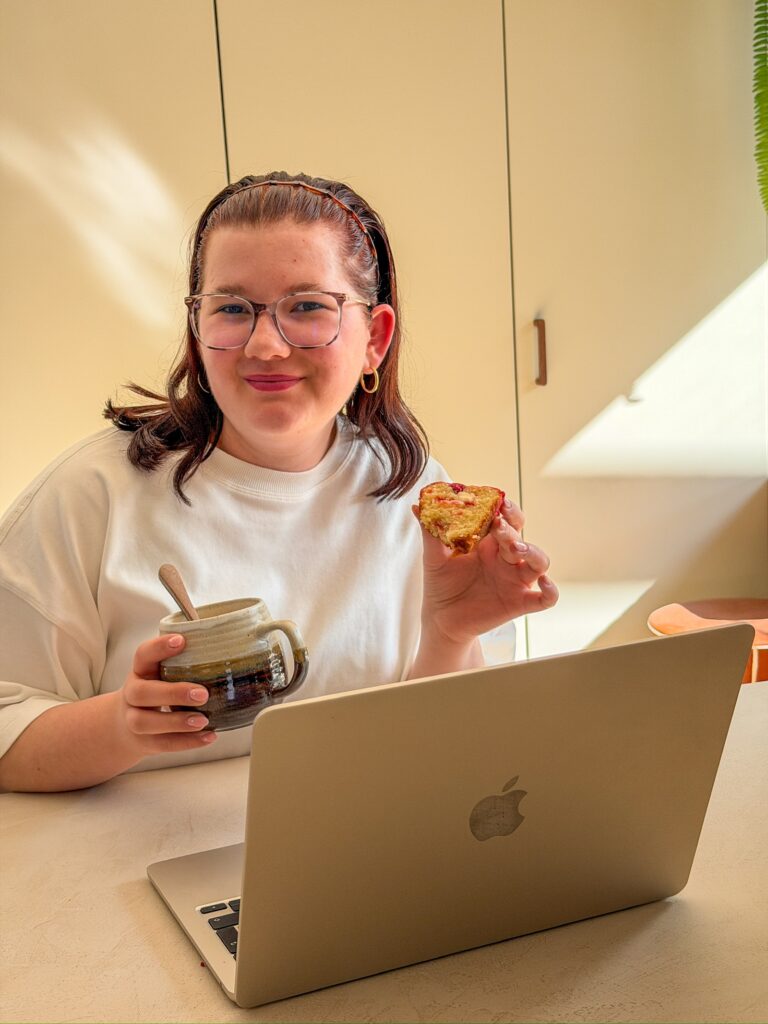 beaudine achter de laptop met koffie en een muffin