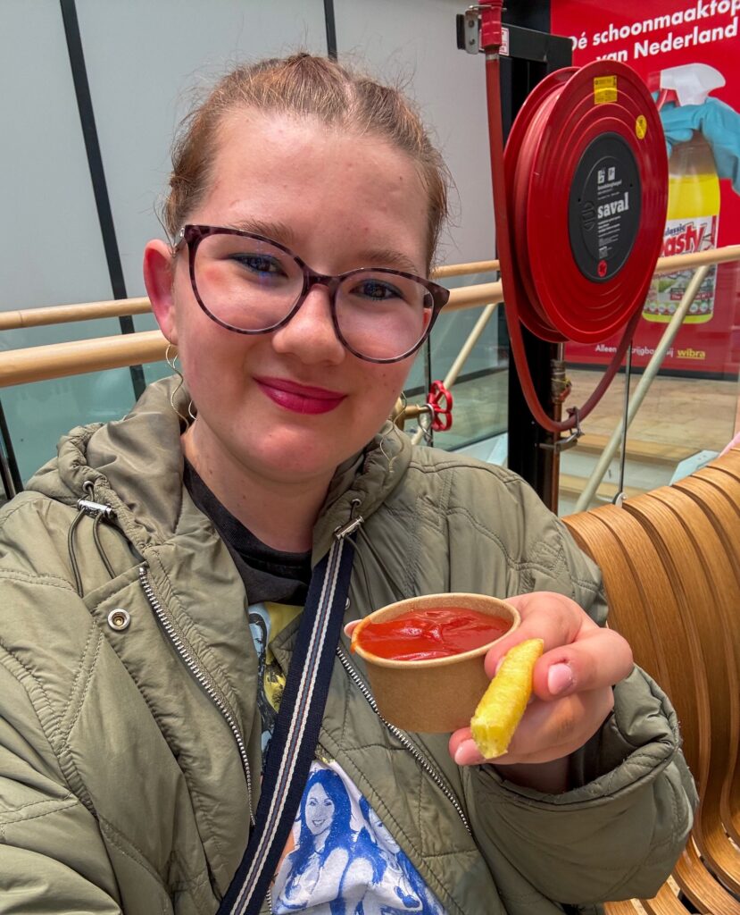 Beaudine eet een patatje met ketchup