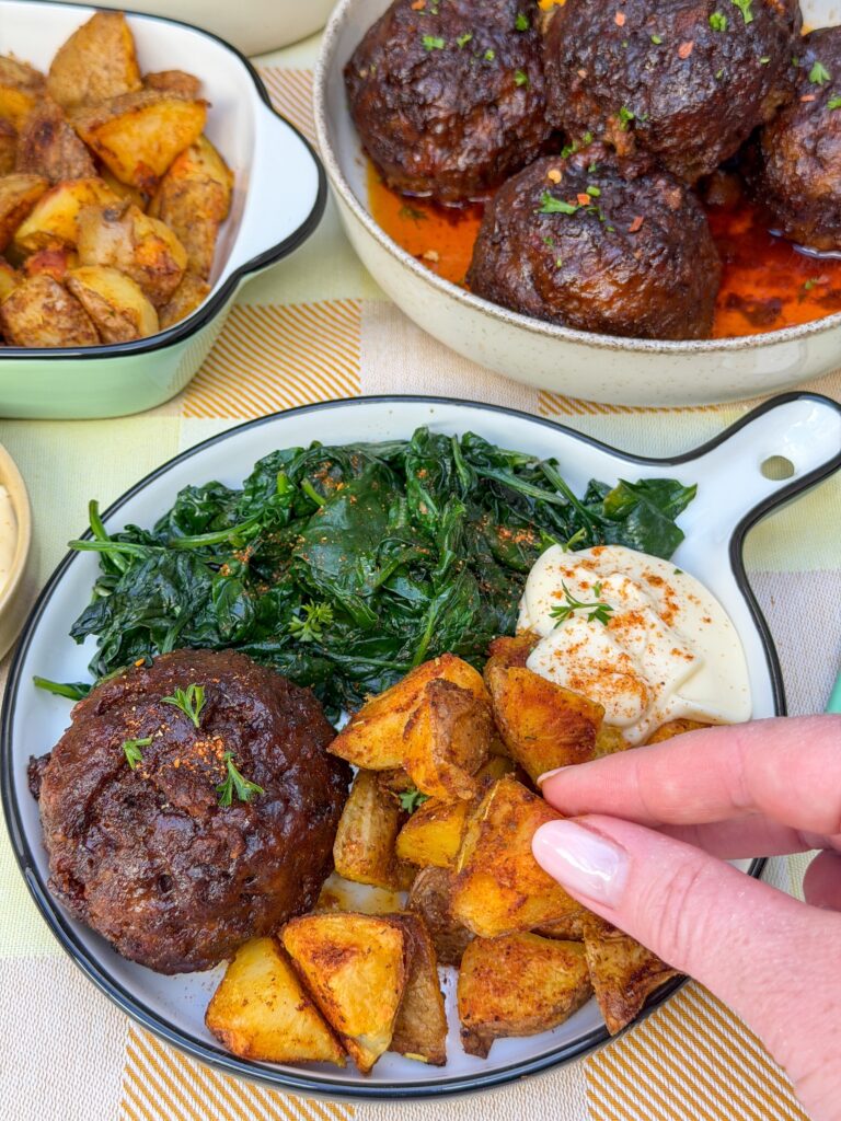 bal gehakt geserveerd met spinazie en krokante aardappels uit de oven