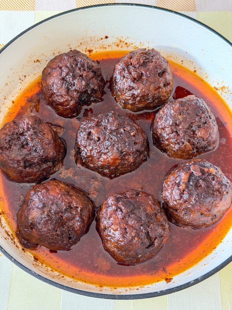 gehaktballen die sudderen in jus in een braadpan