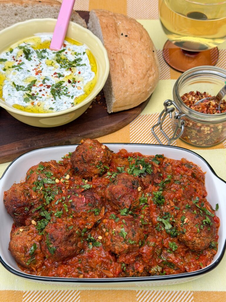 gehakt balletjes in tomatensaus geserveerd met yoghurt munt saus