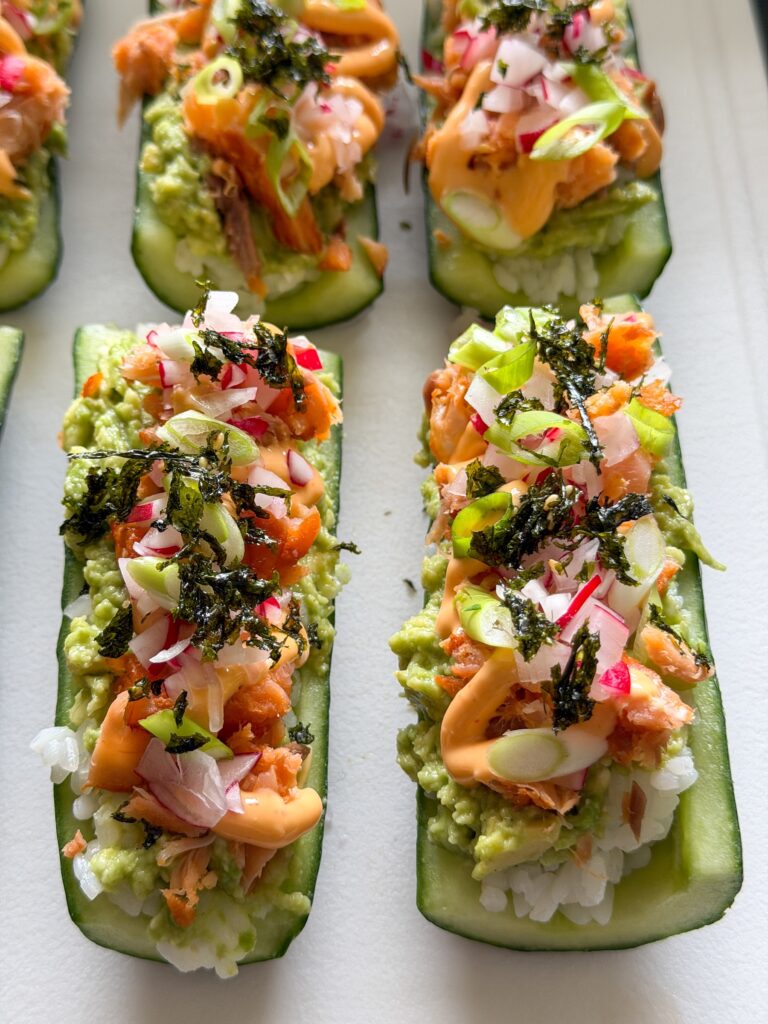 Sushi komkommer bootjes gevuld met zalm en toppings