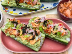 sushi komkommer bootjes met zalm, avocado en sriracha mayonaise op een bord