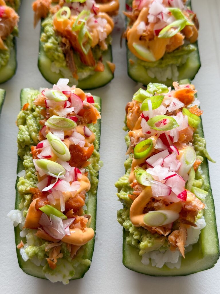 Sushi komkommerbootjes gevuld met sushirijst, zalm en afgetopt met sriracha mayonaise