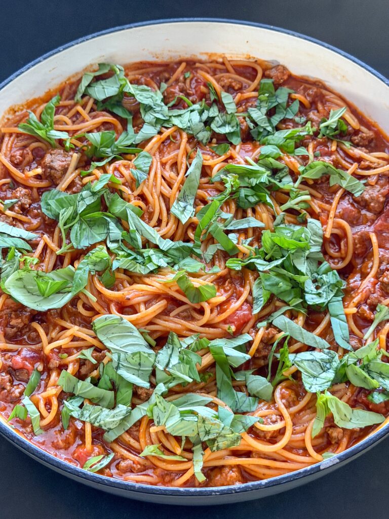 Eenpanspasta met gehakt en tomatensaus in pan met verse basilicum