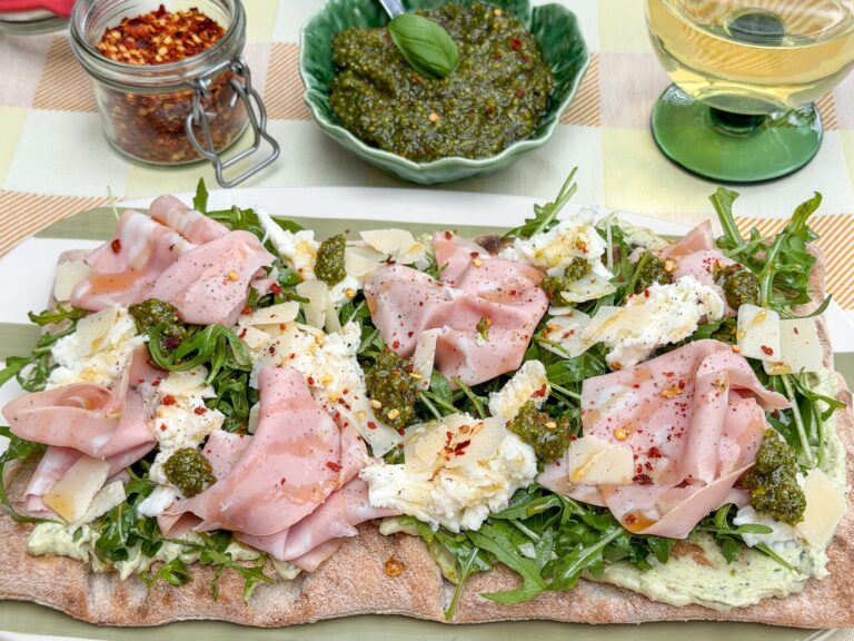 Pinsa met mortadella, pesto, mozzarella en rucola op een serveerschaal