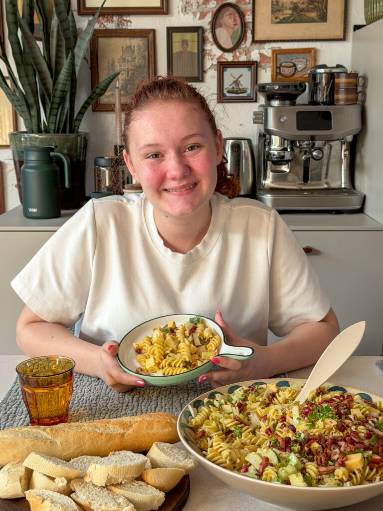 Amaranthe eet een bord pastasalade aan tafel