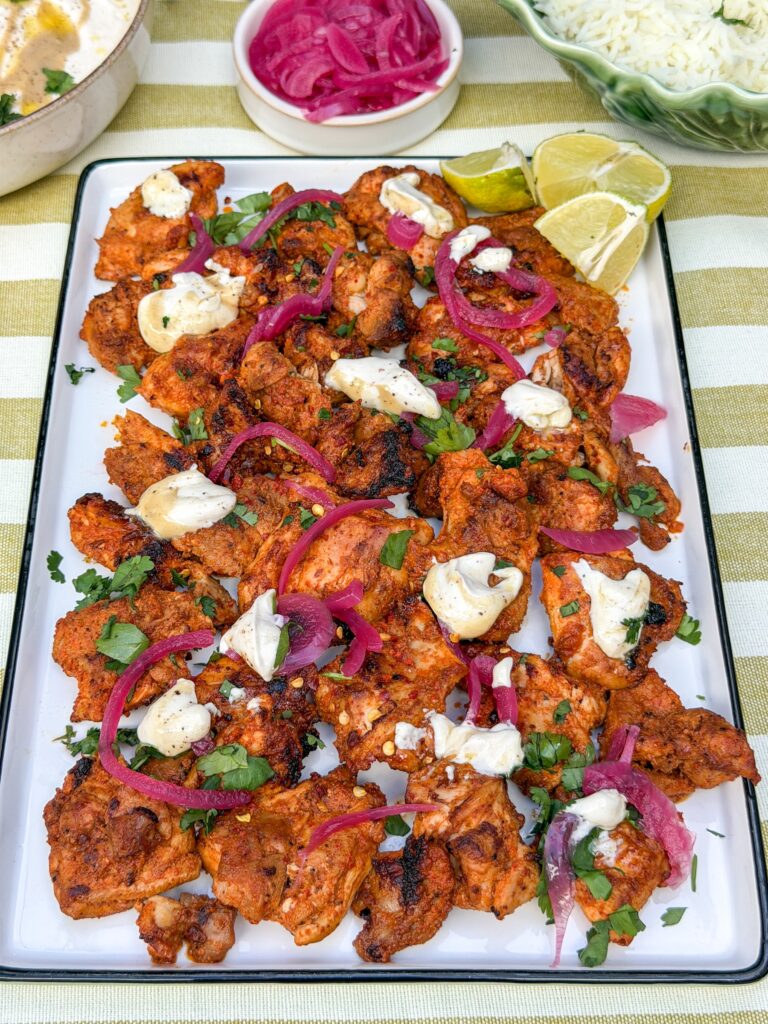 harissa kip met ingelegde rode en tahin yoghurt dressing op witte serveerschaal
