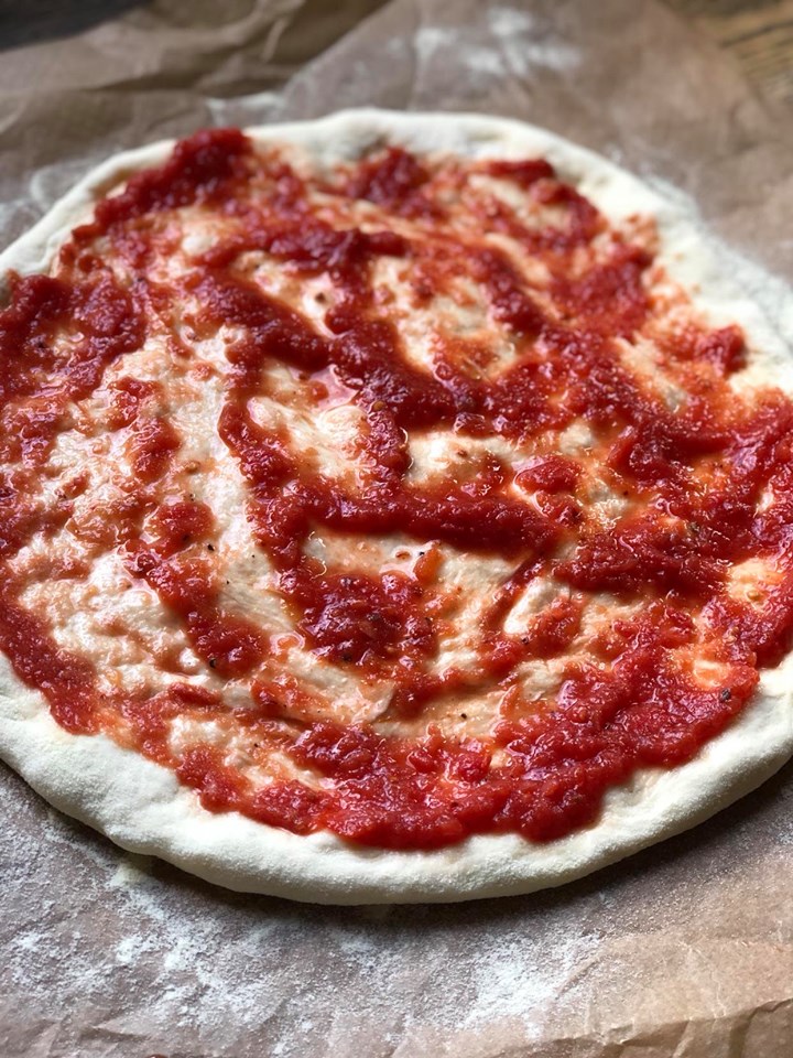 pizzadeeg insmeren met tomatensaus