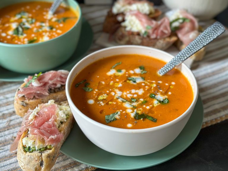 Romige tomatensoep basisrecept een kom met romige tomatensoep geserveerd met verse basilicum