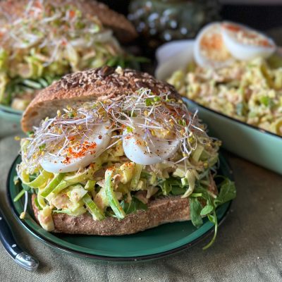 broodje ham prei salade met ei en kerrie geserveerd met verse kiemgroenten op een rond bord