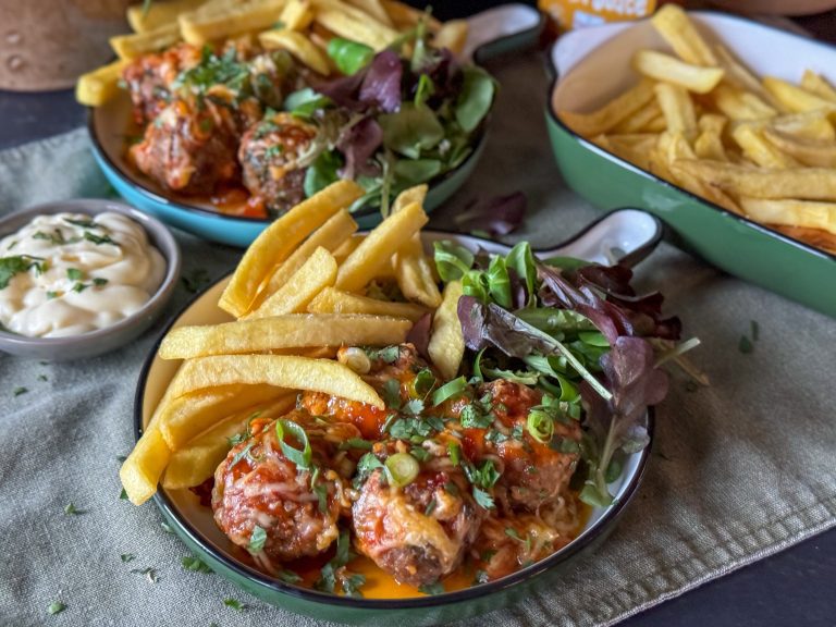 Weekmenu 9 – wat eten we vandaag? 7 makkelijke recepten voor het gezin gehaktballetjes uit de oven met sweet chilisaus geserveerd met frietjes en mayonaise op een rond bord.