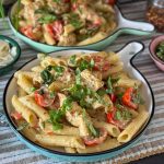 pasta pesto met kip geserveerd op een rond bord met verse basilicum