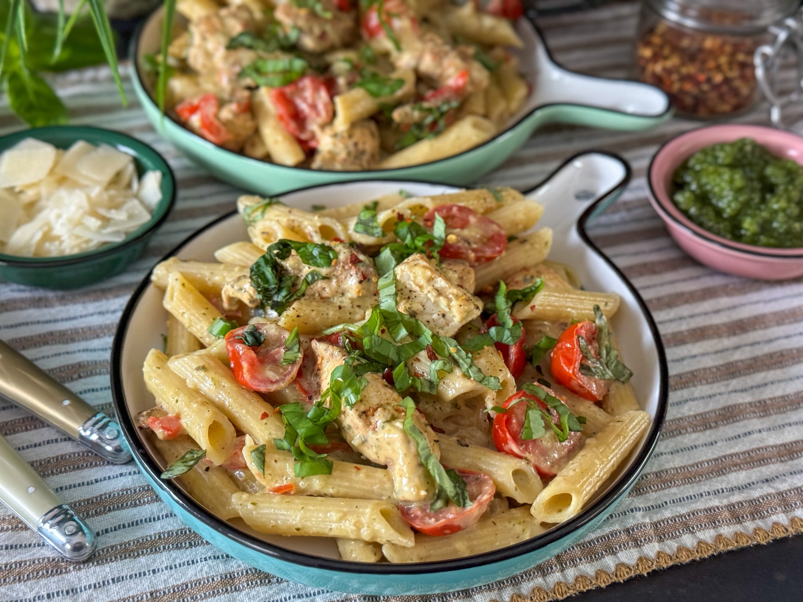 pasta pesto met kip geserveerd op een rond bord met verse basilicum