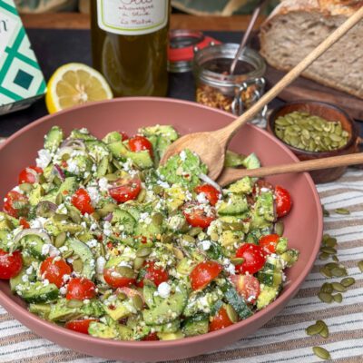 een schaal met een gezonde salade met avocado, feta, tomaatjes en kruidige Italiaanse dressing.