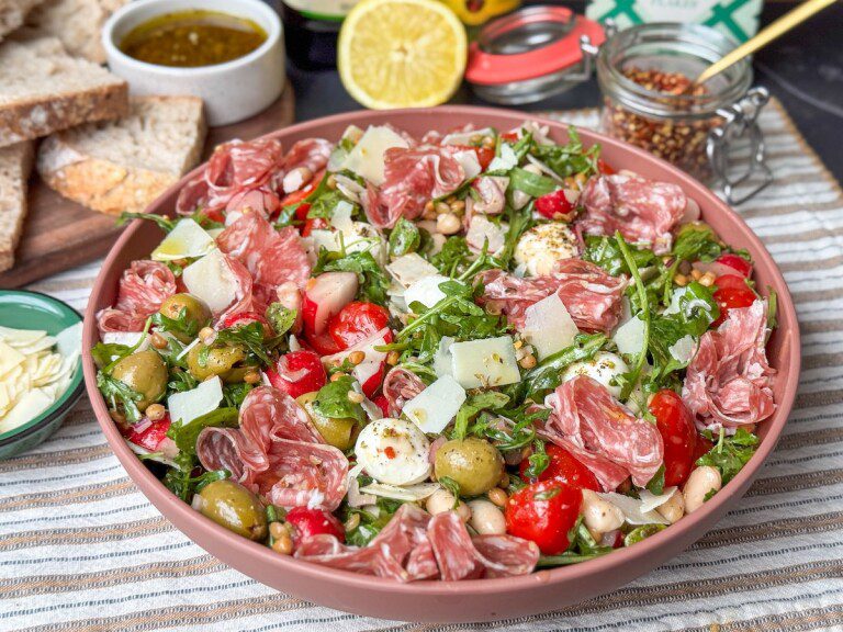 Zomerse Italiaanse salade met mozzarella, bonen en salami Italiaanse salade met salami, olijven en bonen