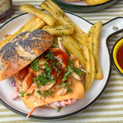 Pulled chicken broodje met hot honey bbq saus pulled chicken broodje met hot honey bbq saus - geserveerd met coleslaw, cheddar en frietjes op bord