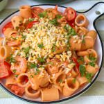 pasta met garnalen recept - in romige tomatensaus geserveerd met kaas en peterselie op rond bord