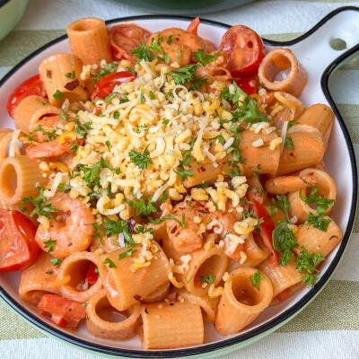 pasta met garnalen recept - in romige tomatensaus geserveerd met kaas en peterselie op rond bord