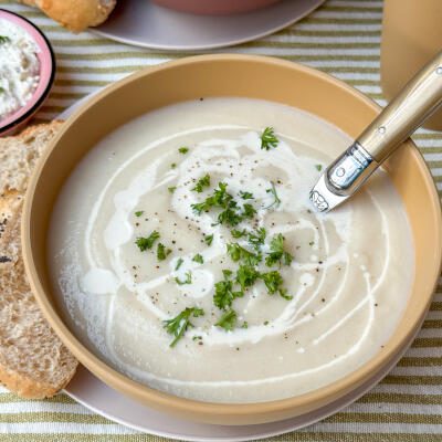 bloemkoolsoep recept - romige soep geserveerd in lichtgele kom met verse peterselie